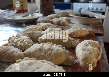 Hausgemachte hässliche Knödel liegen auf einem Brett mit Mehl bestreut. Stockfoto