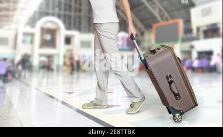 Der untere Teil eines Mannes, der mit einem Koffer durch den Bahnhof von Bangkok läuft. Abenteuer- und Reisekonzept. Stockfoto