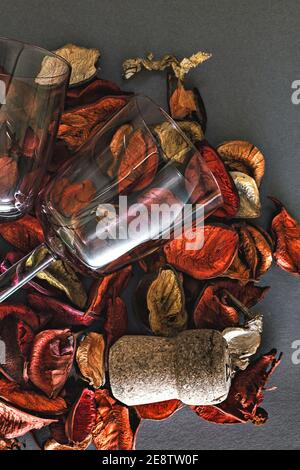 Nahaufnahme von zwei Jahrgangsweingläsern mit Stielen, auf einem Hintergrund von trockenen Rosenblättern. Helles Urlaubskonzept, in Orange- und Gelbtönen. Stockfoto