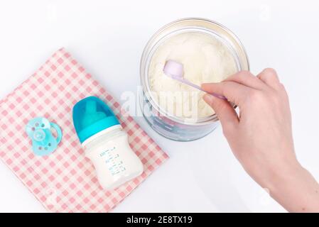 Die Hand der Frau ergreifend einen Messlöffel Milchpulver. Babymilchformel und Babyflaschen Stockfoto