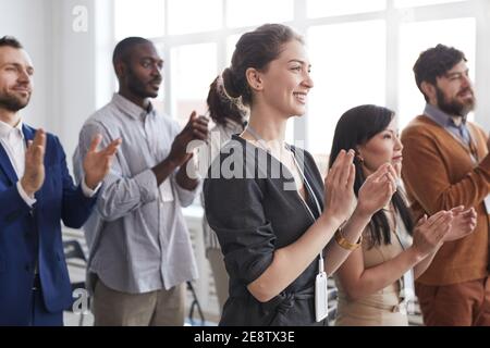 Seitenansicht der multiethnischen Gruppe von Geschäftsleuten, die das Stehen applaudieren Auf einer Geschäftskonferenz oder einem Seminar mit einem Lächeln im Publikum Stockfoto