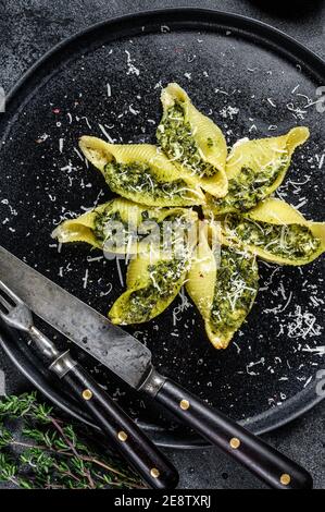 Italienische Jumbo-Schalen Pasta Conchiglioni gefüllt mit Rindfleisch und Spinat auf einem Teller. Schwarzer Hintergrund. Draufsicht Stockfoto
