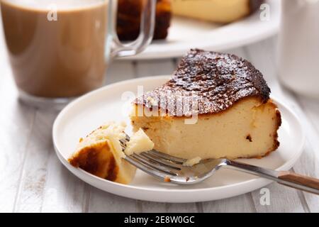 Portion des traditionellen baskischen Käsekuchen mit einer Tasse Kaffee Stockfoto