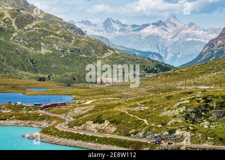 BERNINA Express-Zug am Weissen See in Ospizio Bernina, Oberengadin, Graubünden, Graubünden, Schweiz. Stockfoto