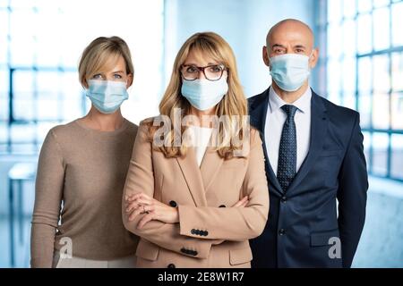 Gruppe von Business-Team zusammen im Büro stehen, während das Tragen von Gesichtsmasken zur Prävention. Stockfoto