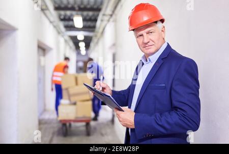 Strenger Leiter einer Spedition mit Checkliste Während der Überprüfung einer Lieferung Stockfoto