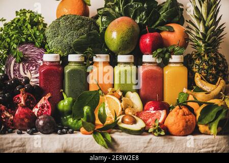 Verschiedene frische Smoothies für Detox Gewichtsverlust Diät-Programm. Bunte Säfte in Vakuumflaschen mit Obst, Gemüse und Gemüse um, weißer Hintergrund. Vegan, vegetarisch, sauberes Essen, alkalische Lebensmittel Stockfoto