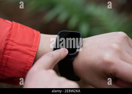 Nahaufnahme einer Frau, die ihre Smartwatch benutzt Natur Stockfoto