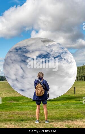 Ein Besucher, der den Sky Mirror von Anish Kapoor auf dem Gelände der Houghton Hall, Norfolk, genießt. Edelstahl, 2018. Stockfoto