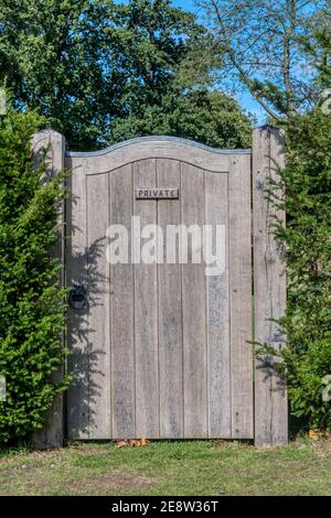 Ein hohes Holztor in einer Eibenhecke, markiert privat. Stockfoto