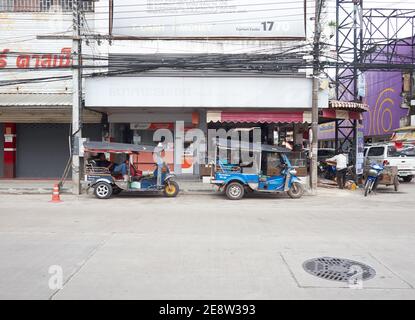 Vor dem Hotel stehen zwei Tuk Tuks oder thailändische Taxis Des Ladens mit Fahrern, die sich in ihnen während des Wartens entspannen Für Passagiere, die ankommen Stockfoto
