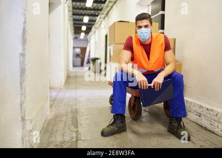 Arbeiter mit Gesichtsmaske wegen Covid-19 im Lager Einer Fabrik macht eine Pause Stockfoto