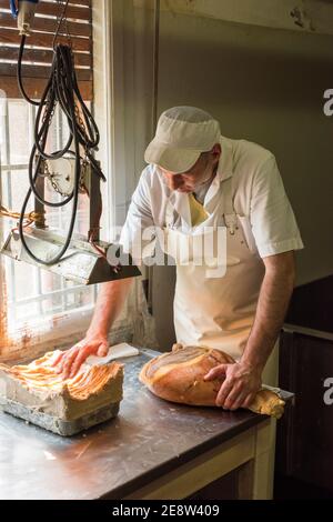 Ein Arbeiter in einer parmaschinken-Fabrik, der Fett zuführt Von Hand, um das Fleisch vor der Reifung zu versiegeln Stockfoto