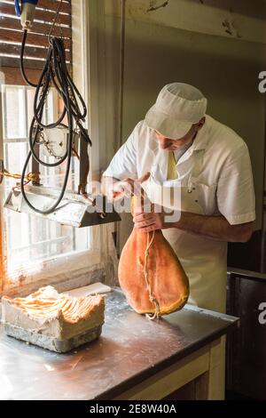 Ein Arbeiter in einer parmaschinken-Fabrik, der Fett zuführt Von Hand, um das Fleisch vor der Reifung zu versiegeln Stockfoto