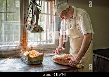 Ein Arbeiter in einer parmaschinken-Fabrik, der Fett zuführt Von Hand, um das Fleisch vor der Reifung zu versiegeln Stockfoto