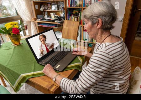 Symbolisches Bild der Telemedizin, ältere Patienten spricht mit einem Arzt in einer Videokonferenz, von zu Hause, Stockfoto