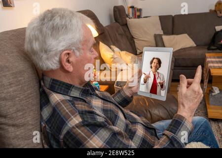 Symbolisches Bild der Telemedizin, ältere Patienten spricht mit einem Arzt in einer Videokonferenz, von zu Hause, Stockfoto