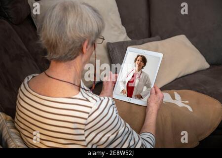 Symbolisches Bild der Telemedizin, ältere Patienten spricht mit einem Arzt in einer Videokonferenz, von zu Hause, Stockfoto