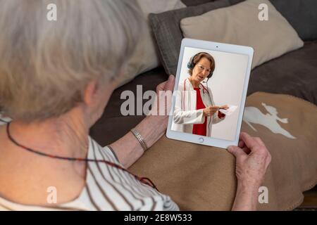 Symbolisches Bild der Telemedizin, ältere Patienten spricht mit einem Arzt in einer Videokonferenz, von zu Hause, Stockfoto