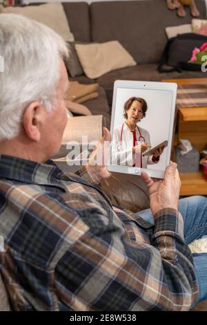 Symbolisches Bild der Telemedizin, ältere Patienten spricht mit einem Arzt in einer Videokonferenz, von zu Hause, Stockfoto