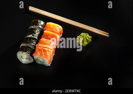 Benutzerdefinierte Sushi-Rolle in Tempura mit Nori, frischem Lachs, Thunfisch, Avocado, Masago-Kaviar, beträufelt mit Ananassauce mit Salat gießen als Dekoration auf Stockfoto