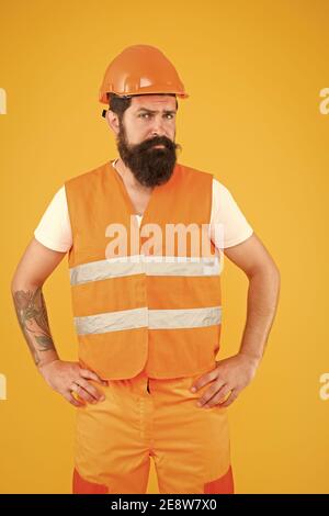 Mann im Bau. Arbeitsmann gelben Hintergrund. Bärtiger Mann in Schutzhut und Sicherheitsweste. Geschickter Mann mit Bart und Schnurrbart. Renovierung und Reparatur. Bau und Bau. Stockfoto