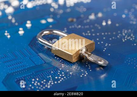 Vorhängeschloss mit Schlüssel auf blauer Leiterplatte. Das Konzept der Verschlüsselung, des Informationsschutzes, der Datensicherheit. Stockfoto