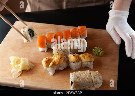 Frau essen geliefert Sushi aus einem Behälter mit japanischen Sticks Stockfoto