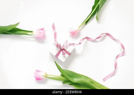 Frühling rosa Tulpenblumen und Geschenkbox auf weißem Hintergrund von oben in flacher Lage. Herzlichen Glückwunsch zum Frauentag oder zum Muttertag. Stockfoto