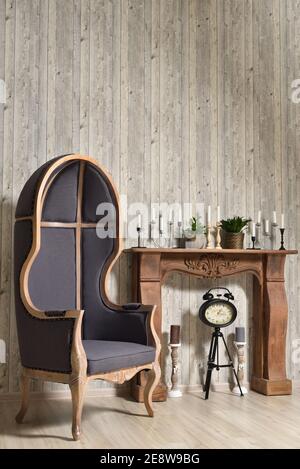 Hölzerne Retro-Interieur mit großer Haube Stuhl und Kamin mit Kerzen Stockfoto