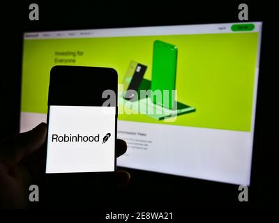 Person, die Smarthone mit Logo des US-Finanzdienstleisters Robinhood Markets Inc. Auf dem Display vor der Website hält. Fokus auf Telefonbildschirm. Stockfoto