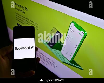 Person, die Mobiltelefon mit Logo des US-Finanzdienstleisters Robinhood Markets Inc. Auf dem Display vor der Webseite hält. Fokus auf Telefonbildschirm. Stockfoto