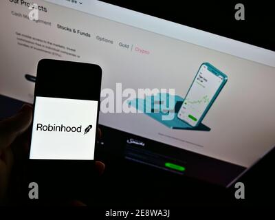 Person mit Mobiltelefon mit Logo des US-Finanzdienstleisters Robinhood Markets Inc. Auf der Anzeige vor der Website. Fokus auf Telefonbildschirm. Stockfoto