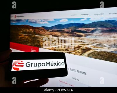 Person, die Mobiltelefon mit Logo des mexikanischen Bergbauunternehmens Grupo México auf dem Bildschirm vor der Business-Website hält. Konzentrieren Sie sich auf die Telefonanzeige. Stockfoto