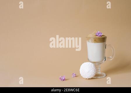 Schöner Dalgon Kaffee Drink mit Schaum in einer transparenten Tasse und Marshmallows auf einem beigen Hintergrund. Speicherplatz kopieren Stockfoto