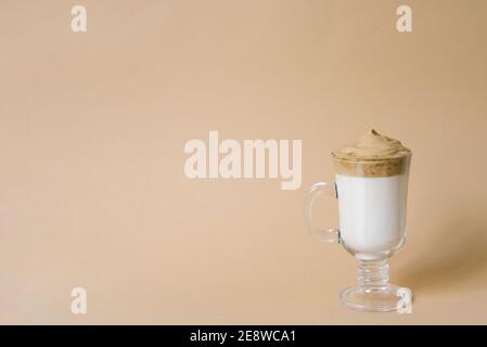 Schöne Dalgon trinken Kaffee mit Schaum in einem transparenten Becher Auf einem beigen Hintergrund mit Leerzeichen kopieren Stockfoto