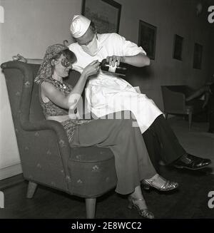 Maskerade in den 1940er Jahren. Ein Mann, der als Arzt gekleidet ist, bietet einer Haremdame ein Getränk aus einer Apothekenflasche an. Schweden 1945 Kristoffersson Ref L99-2 Stockfoto