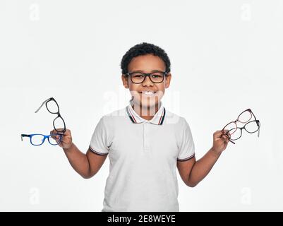 Afroamerikanischer Junge hält viele stilvolle Brillen in den Händen, für Sehkorrektur für Kinder, auf weißem Hintergrund Stockfoto