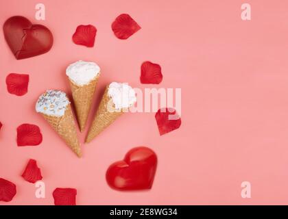 Zwei rote Herzen, Eis und Rosenblätter auf rosa Hintergrund Stockfoto