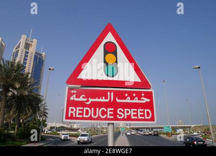 Ein Straßenschild in arabischer und englischer Sprache, das den Autofahrern sagt, dass sie wegen der Ampeln die Geschwindigkeit reduzieren sollen, Manama, Königreich Bahrain Stockfoto