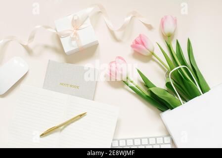 Tulpen, Geschenkbox und Kaffee auf beigem Hintergrund. Flach liegend. 8. März, Internationaler Frauentag. Valentinstag. Arbeitsplatz des Bloggers Stockfoto