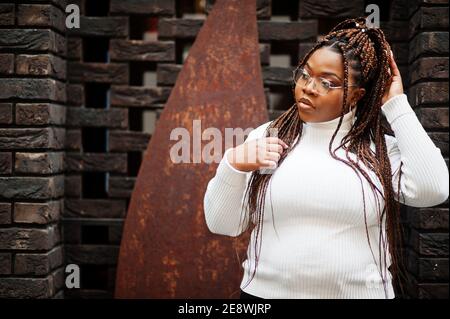 Glamouröse afroamerikanische Frau in weißen Rollkragenpullover Pose auf der Straße. Stockfoto