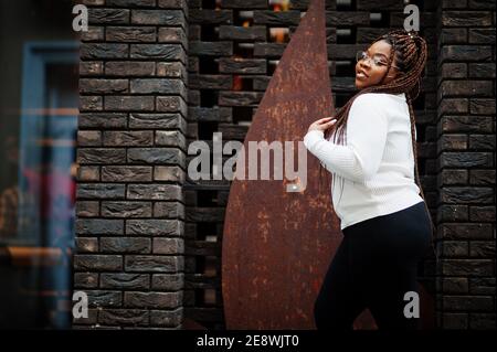 Glamouröse afroamerikanische Frau in weißen Rollkragenpullover Pose auf der Straße. Stockfoto