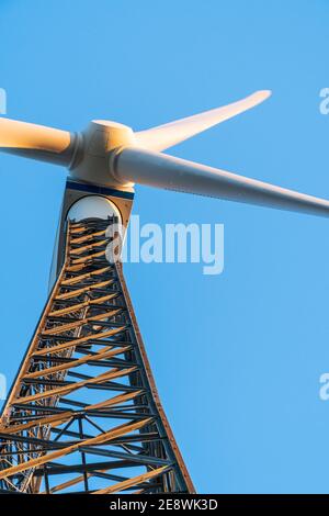Windturbine gegen einen klaren blauen Himmel. Metallstruktur mit Streben und Nieten an einem Windturbinenpark an einem sonnigen Tag. Low-Angle-Ansicht, Nahaufnahme. Stockfoto