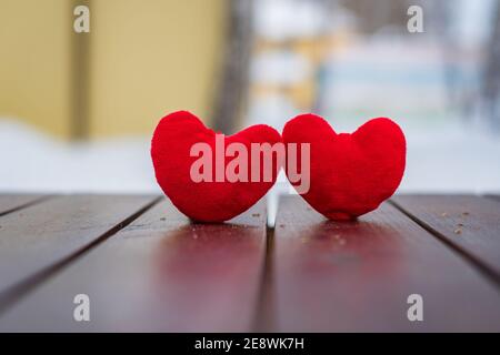 Valentinstag, zwei rote Herzen stehen auf einer braunen Holzoberfläche auf einem abstrakten Hintergrund Stockfoto