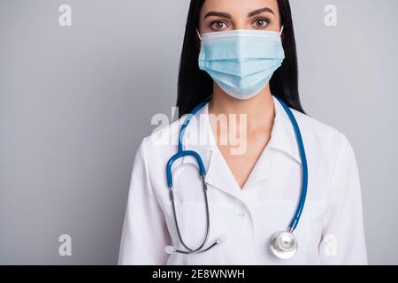 Abgeschnitten Foto von liebenswert positive Frau Therapeut gekleidet weißen Uniform Gesichtsmaske isoliert grauen Hintergrund Stockfoto