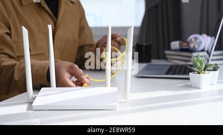 Nahaufnahme des man-Steckers Internet-Kabel in den Router. WLAN-Internet-Konzept. Stockfoto