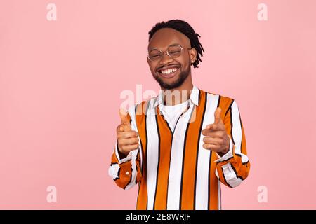 Hey, du! Aufgeregt glücklich afro-amerikanischen Mann mit Bart und Dreadlocks im gestreiften Hemd zeigt Finger auf Sie und lächelt, Sie sind die besten. Stehbolzen für den Innenbereich Stockfoto