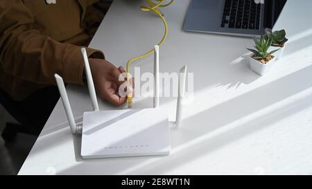 Nahaufnahme des Mannes, der das Kabel an den Wireless-Router anschließt. WLAN-Internet-Konzept. Stockfoto