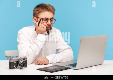Gelangweilt nachdenklichen Mann Grafik-Designer hält Stift der Grafik-Tablet in der Hand und Blick auf Laptop-Display, Zeichnung Skizzen, Entwicklung von Design. Ind Stockfoto